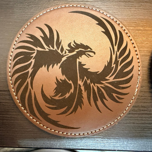Round leather coaster with a dragon design on a wooden surface