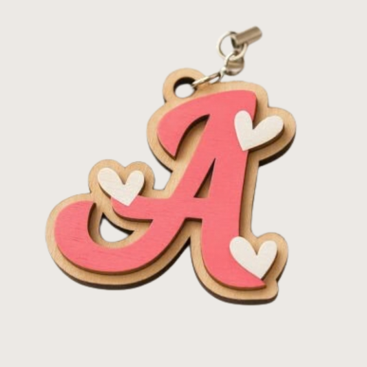 Keychain with a pink letter 'A' and white hearts on a beige background